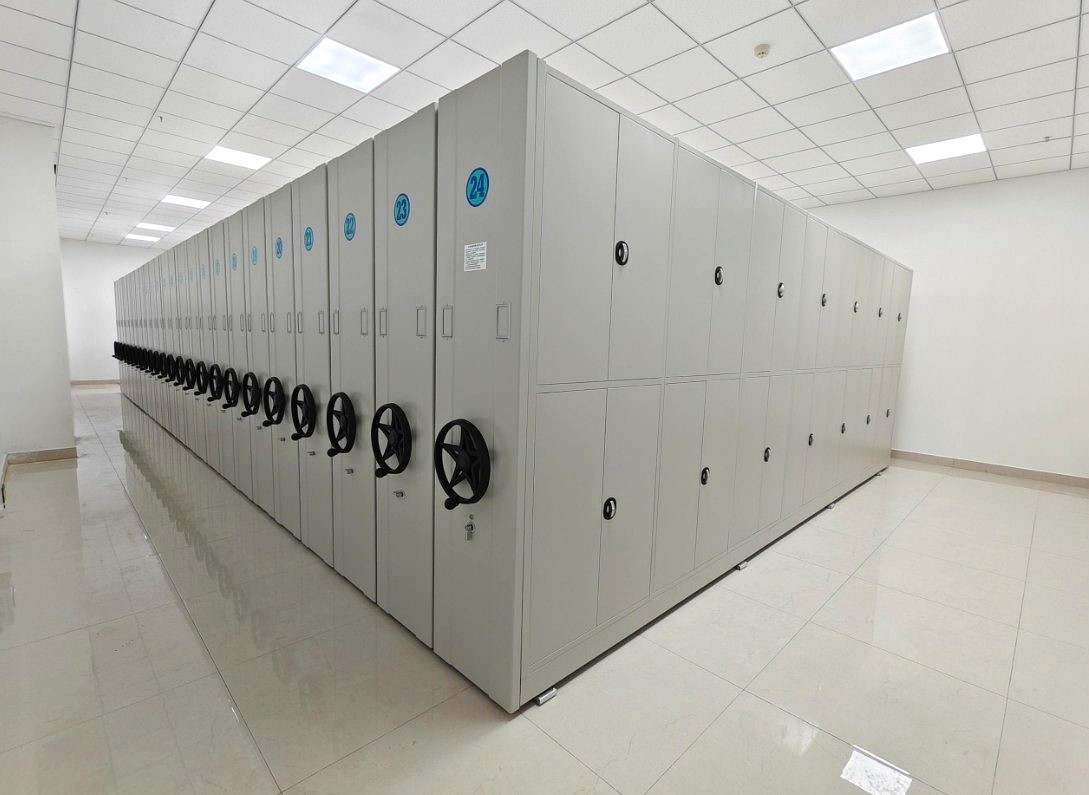 Assembled double-sided manual mobile shelving with folding handwheels in a customer archive room